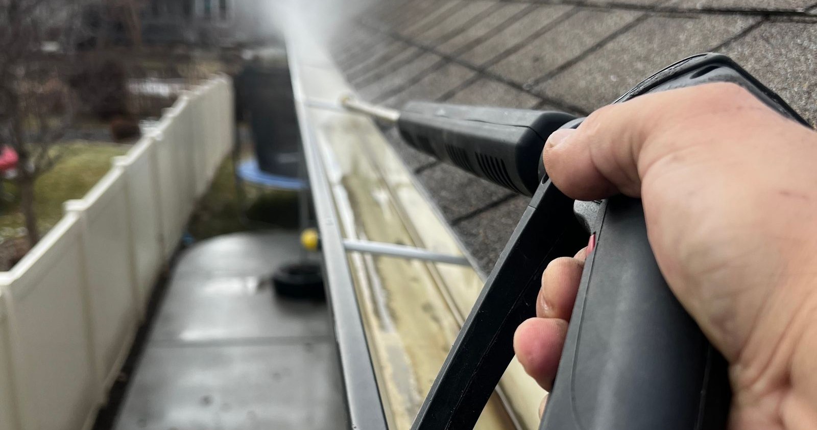 Debris and water being cleaned from a home rain gutter